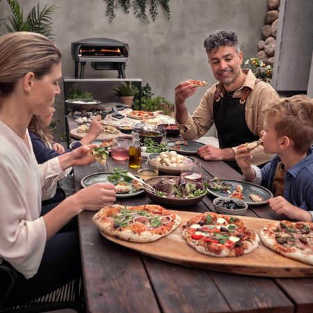 Glückliche Familie sitzt am Tisch uns isst gegrillte Pizza
