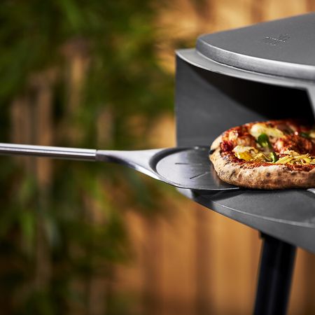 Pizza die in den Grillofen geschoben wird